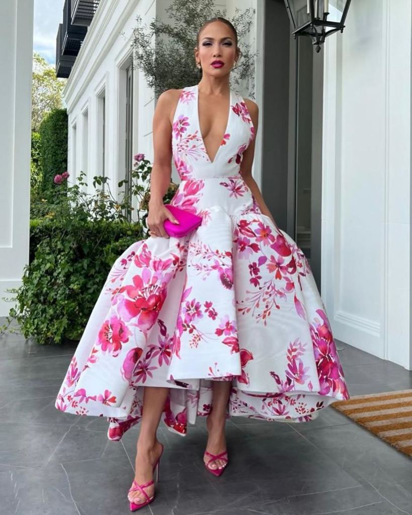 Jennifer Lopez poses in floral white and pink dress with a poofy skirt and deep neckline
