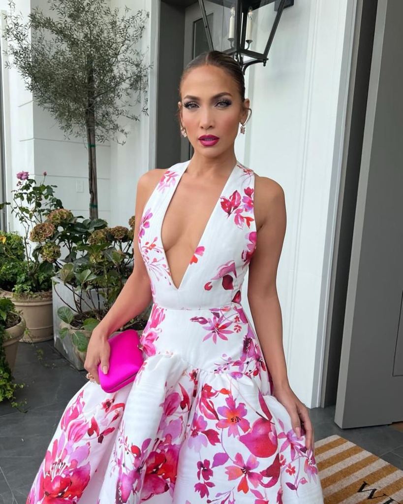 Jennifer Lopez poses in floral white and pink dress with a poofy skirt and deep neckline